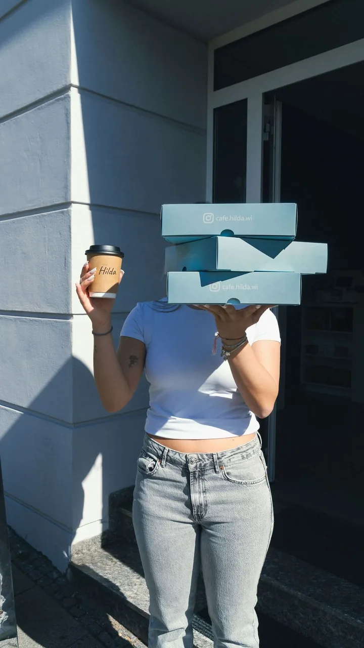 Ein Stapel Cookie-Boxen in den Händen